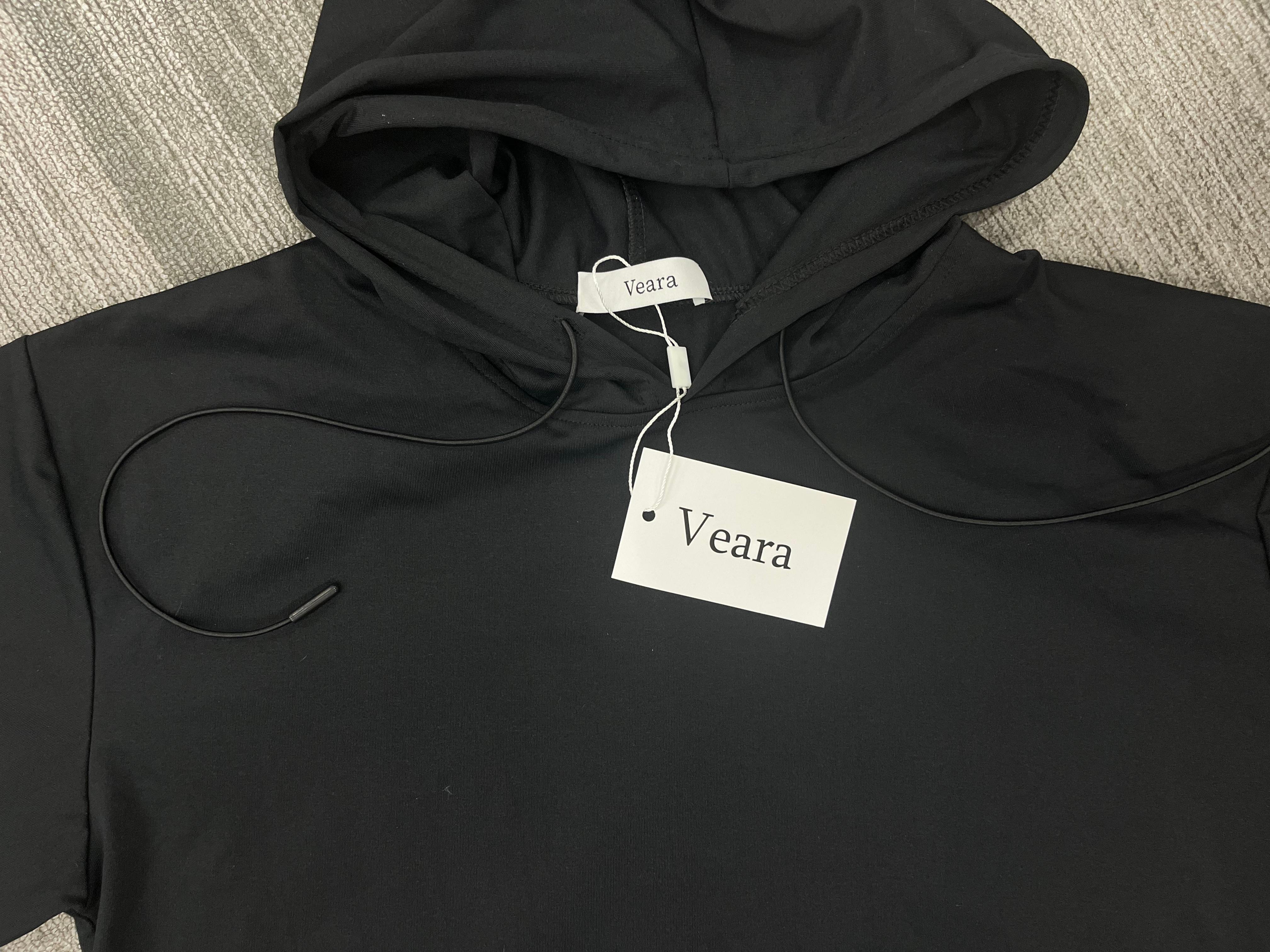 Veara black draped hoodie laid flat with visible label detail.